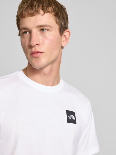 Mężczyznęmodel nosi T-Shirt aus Baumwoll-Mix Modell 'EVOLUTION' von The North Face, biały, krój regular fit, okrągły dekolt, label-print, długość tyłu w rozmiarze M: 69 cm, zbliżenie na górną część ciała