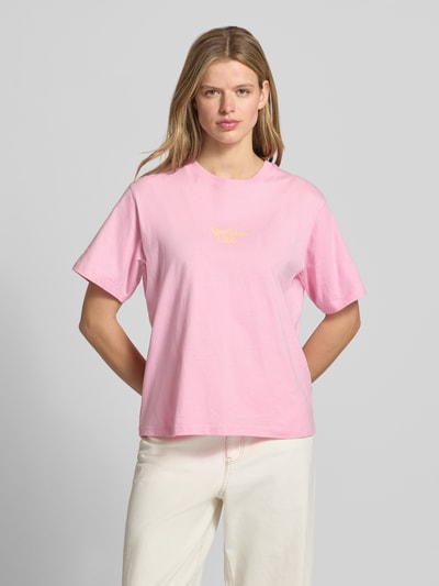 Frauenmodel trägt Damen T-Shirt mit Statement-Print Modell 'SENNA' von JJXX in Rosa aus Reine Baumwolle, Loose-Fit, Gerippter Rundhalsausschnitt, Rückenlänge bei Größe S 60 cm, Ganzkörperansicht von vorne.