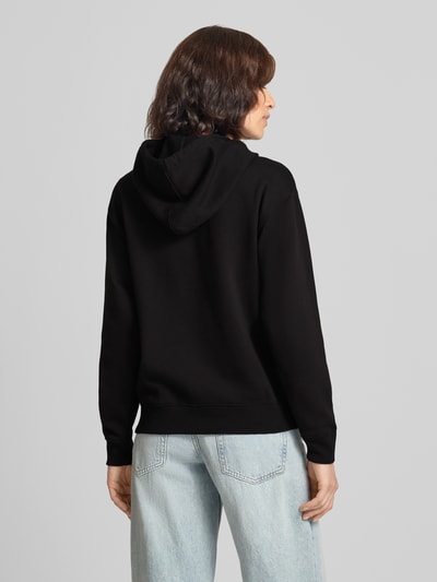 Vrouwenmodel draagt zwarte sweatjack met capuchon, katoenmix, relaxed fit, GAP Model 'HERITAGE', kangoeroezak, logo, rugaanzicht