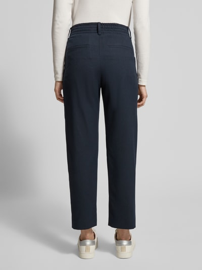 Frauenmodel trägt Stoffhose mit Gesäßtaschen Modell 'DISPATCH' von Drykorn, dunkelblau, Regular Fit, glatte Textur, Ganzkörperansicht Rückansicht.
