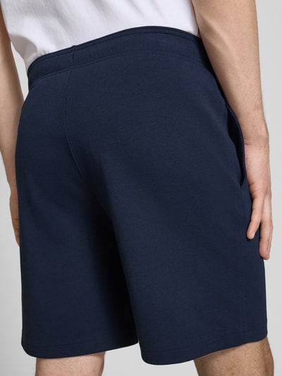 Männermodel trägt Shorts mit Label-Stitching mit elastischem Bund von CHAMPION in Dunkelblau, Baumwoll-Mix, Nahaufnahme Rückansicht.
