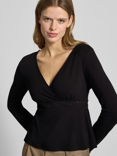 Vrouwenmodel draagt slim fit langarmshirt uit viscosemix met kant, diepe V-hals en label stitching, model 'SINI' van Only, close-up bovenlichaam.