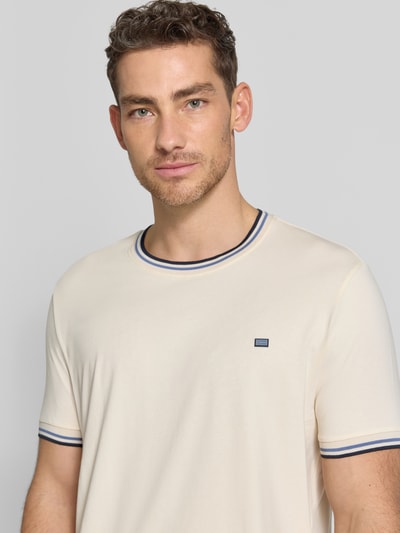 Męski model nosi T-Shirt mit Kontraststreifen und Rundhalsausschnitt von Christian Berg Men, bawełna z elastanem, krój regular fit, jasny kolor, kontrastowe paski przy dekolcie i rękawach, widoczne małe logo z przodu, ujęcie: zbliżenie na górną część ciała.