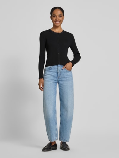 Frauenmodel trägt schwarze Slim Fit Strickjacke aus Viskose-Mix Modell 'Wonder' von Vero Moda, Optik: Unifarben, Spitzen-Besatz, Rippstrick, Rundhals, Langarm; Ganzkörperansicht von vorne.