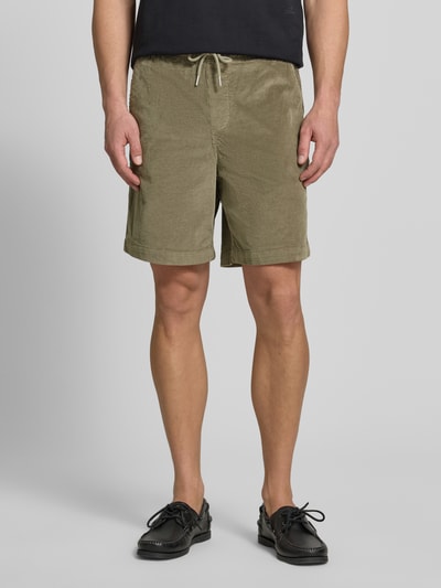 Męski model nosi Regular Fit Sweatshorts aus Baumwoll-Mix od SELECTED HOMME, bawełniany sztruks, jednolity, elastyczny pas, kieszenie, kolor oliwkowy, krój regular fit, zdjęcie całej sylwetki z przodu.