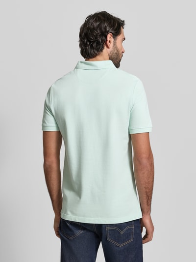 Männermodel trägt Regular Fit Poloshirt aus reiner Baumwolle von s.Oliver RED LABEL in Uni-Optik, Piqué-Struktur, Ganzkörperansicht Rückansicht.