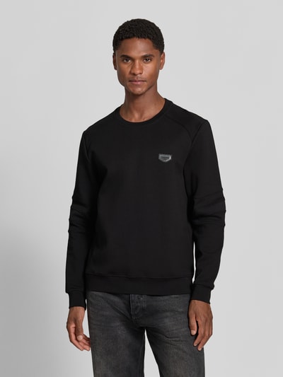 Männermodel trägt zwart heren sweatshirt met labelpatch Model 'NEUTER' van Antony Morato, getailleerd, ronde hals, mouwen met verstevigingen, elastische boorden, ruglengte maat M 66 cm, mouwlengte maat M 58 cm, Ganzkörperansicht van voren.