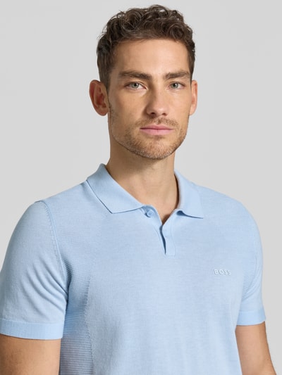 Männermodel trägt Poloshirt mit Logo Detail von BOSS Green in Hellblau, Optik: Unifarben, Passform: Regular-Fit, Logo-Print, Polokragen, Bodymapping-Struktur, Nahaufnahme Oberkörper.