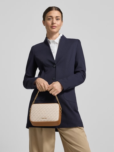 Frauenmodel trägt Umhängetasche mit Label-Detail Modell 'BRYANT' von MICHAEL Michael Kors, cremefarben gemustert, goldfarbener Kettengriff, Nahaufnahme Oberkörper.