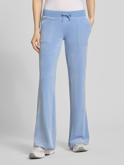 Frauenmodel trägt Low Rise Sweatpants mit Eingrifftaschen Modell 'LAYLA' von Juicy Couture, hellblauer Farbton, Material-Mix mit Stretch-Anteil, elastischer Bund, Vorderansicht, Nahaufnahme Unterkörper. Innenbeinlänge bei Größe S: 82 cm.