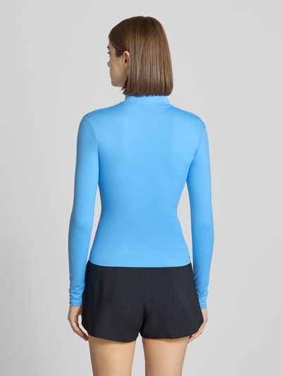 Modelka kobieca ma na sobie kurtkę treningową z długim rękawem w kolorze niebieskim, styl kurtki treningowej Slim Fit Trainingsjacke mit Stehkragen model 'One Fitted' od Nike, damska kurtka treningowa, widok całej sylwetki z tyłu