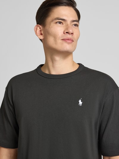 Męski model nosi Relaxed Fit T-Shirt mit Label-Stitching od Polo Ralph Lauren, czarna bawełna, okrągły dekolt, detal z logo, półzbliżenie górnej części ciała.