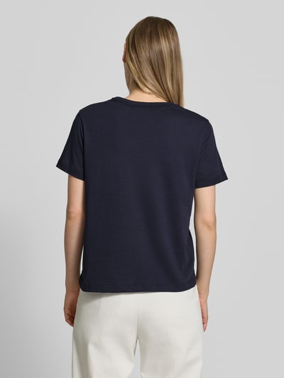 Frauenmodel trägt T-Shirt mit Label-Print und Rundhalsausschnitt von Gant aus Reine Baumwolle, Regular-Fit, dunkelblau, Rückenlänge 57 cm bei Größe S, Ganzkörperansicht Rückansicht.