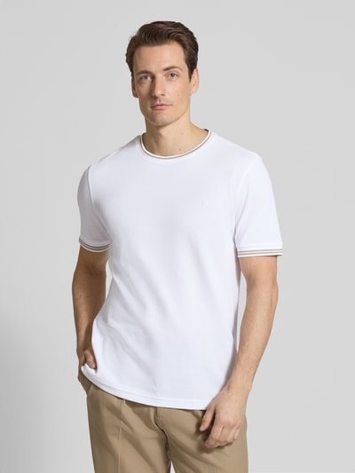 Męski model nosi T-shirt mit Strukturmuster und Rundhalsausschnitt von Christian Berg Men, mieszanka bawełny i elastanu, krój regular fit, fakturowany wzór, okrągły dekolt, długość tyłu w rozmiarze M: 70 cm, biały kolor, gładka tekstura, widok całej sylwetki z przodu.