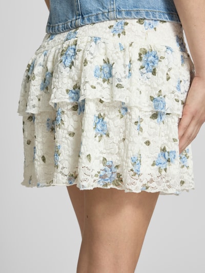 Frauenmodel trägt Ausgestellter Mini-Rock mit Allover-Muster Modell 'SAGA' von Only, zartes Weiß mit blauen Blumen, Damen Mini-Rock, Nahaufnahme Oberschenkel.