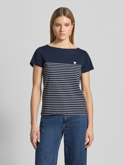 Frauenmodel trägt Regular Fit T-Shirt aus reiner Bio-Baumwolle von Tom Tailor mit Allover-Streifenmuster, Herz- und Label-Print, U-Boot-Ausschnitt, Kurzarm, strukturiert in Dunkelblau und Weiß, Ganzkörperansicht von vorne.