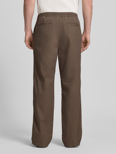 Männermodel trägt Leinenhose mit elastischem Bund und Eingrifftaschen von GAP in Braun, lockerer Schnitt, Ganzkörperansicht Rückansicht. Loose Fit im Leinen-Mix mit Baumwoll-Anteil, französische Eingrifftaschen, Gesäßleistentaschen, Bundweite bei Größe M 43 cm, Innenbeinlänge 80 cm.