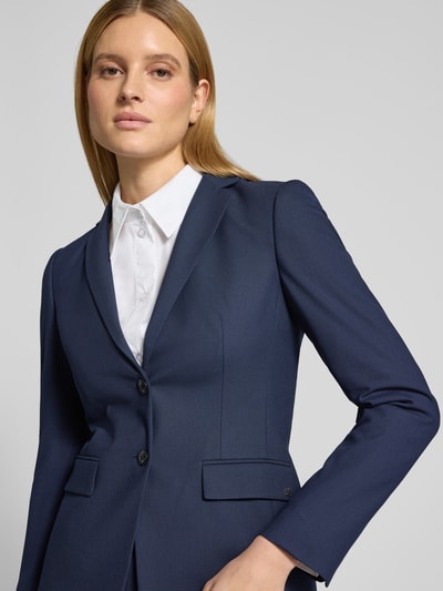 Modelka kobieca nosi Slim Fit Longblazer mit Viskose-Anteil Modell 'ADALAS' od HUGO, granatowy, z klapami, zapięcie na 2 guziki, patki, detal z logo, poduszki na ramionach, krój slim fit, widok z przodu na górną część ciała.