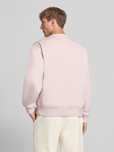 Männermodel trägt Sweatshirt mit Label-Details von Champion in zartem Rosa aus Baumwoll-Mix, lockere Passform, Rückenansicht, Ganzkörperansicht Rückansicht.