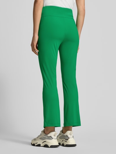 Frauenmodel trägt Loose Fit Jogpants mit breitem Bund von Marc Cain in Grün, Elastischer-Material-Mix, Teilungsnähte, Reißverschlusstasche, Ganzkörperansicht Rückansicht.