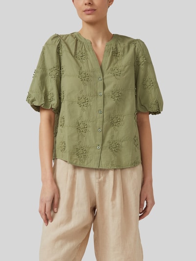 Frauenmodel trägt Regular Fit Kurzarmbluse aus reiner Baumwolle von s.Oliver RED LABEL in Olivgrün mit floralem Strukturmuster, Nahaufnahme Oberkörper.