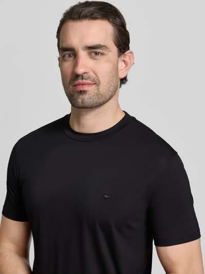 Männermodel trägt Regular Fit T-Shirt mit Rundhalsausschnitt von Emporio Armani, schwarzer Modal-Mix, Kurzärmel, Nahaufnahme Oberkörper.