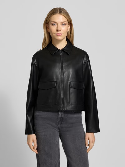 Kobiece model prezentuje czarną kurtkę w stylu skóry Jacke in Leder-Optik Modell 'Josmica' od OPUS, klasyczny fason, widok z przodu, ujęcie całej sylwetki.