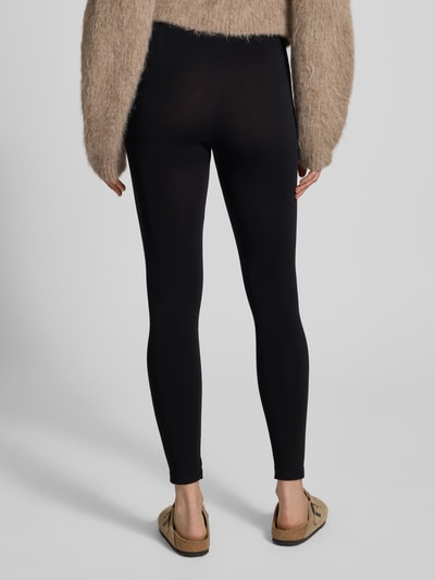 Frauenmodel trägt schwarze Leggings aus Viskose-Mix im nahtlosen Design Modell 'BAMBOO' von MAGIC Bodyfashion, enganliegend, elastischer Bund, unifarben, feuchtigkeitsabsorbierend, Ganzkörperansicht Rückansicht.