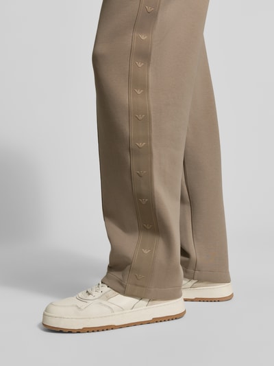 Männermodel trägt Regular Fit Sweathose mit Label-Details von Emporio Armani aus Baumwoll-Mix mit Stretch-Anteil, Bundfalten, Nahaufnahme Beine.