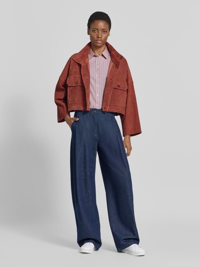 Frauenmodel trägt Regular Fit Langarmbluse aus reiner Baumwolle von GANT mit Streifen in Rot und Weiß, kombiniert mit weiter Jeans, Ganzkörperansicht von vorne.