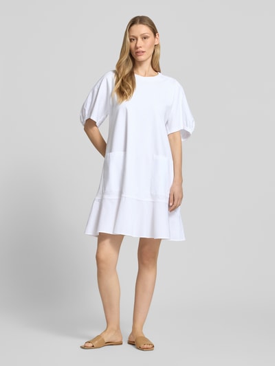 Modelka kobieca nosi białą sukienkę tunikową do kolan z bufkami, model 'ONORE' od MM by Max Mara, bawełna z domieszką stretchu, linia A, okrągły dekolt, długość pleców w rozmiarze S: 90 cm, szerokość w rozmiarze S: 50 cm, długość rękawa w rozmiarze S: 30 cm, gładki materiał, prosty fason, widok całej sylwetki od przodu.