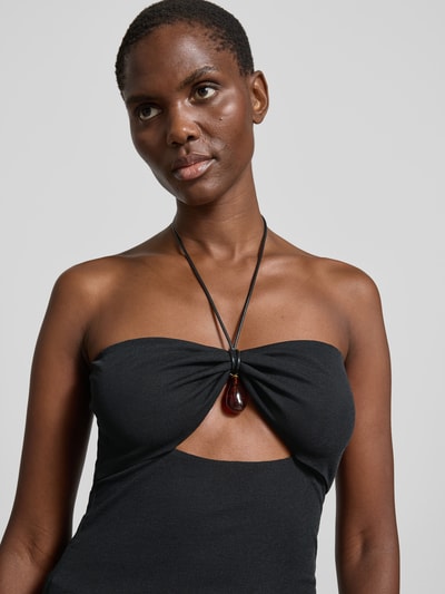 Frauenmodel trägt Neckholder-Top mit Zierstein von Nanushka in Schwarz, Bandeau-Design, Cut-Out, Spaghettiträgern, Nahaufnahme Oberkörper.