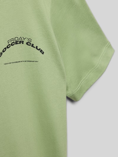 Mädchen trägt Regular Fit T-Shirt aus reiner Baumwolle von s.Oliver RED LABEL in Optik: Unifarben mit Motiv-Print, Nahaufnahme Oberkörper.