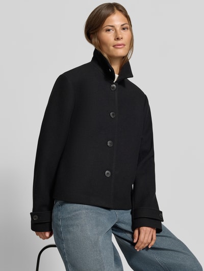 Frauenmodel trägt Regular Fit Jacke mit durchgängiger Knopfleiste von MYON in Schwarz, Umlegekragen, langärmlig, glatte Textur, Brustweite 54 cm, Rückenlänge 58 cm, Schulterbreite 43 cm, Ärmellänge 64 cm, Ganzkörperansicht von vorne.