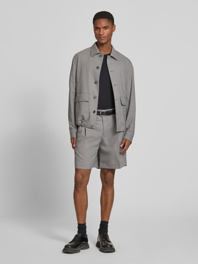 Männermodel trägt Loose Fit Bermudas mit Gesäßtaschen von bugatti, Woll-Mix mit Baumwoll-Anteil in Grau, Bund mit Bügelfalten, Ganzkörperansicht von vorne.