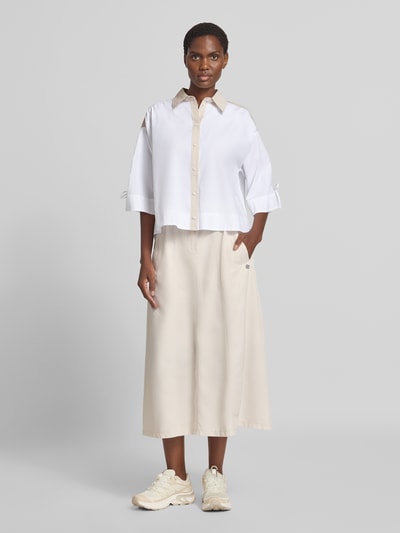 Frauenmodel trägt Boxy Fit Bluse mit 3/4-Arm von Marc Cain in Weiß, reine Baumwolle, Hemdblusenkragen, Knopfleiste, Ganzkörperansicht von vorne.