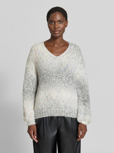Kobieta modelka nosi sweter z dzianiny 'Strickpullover aus Effektgarn mit V-Ausschnitt' od Apricot, Mieszanka materiałów z dodatkiem wełny, krój regular fit, efektowna przędza, dekolt w serek, Długość tyłu w rozmiarze S: 46 cm, Długość rękawów w rozmiarze S: 49 cm, melanżowe odcienie bieli i szarości, miękka faktura, widoczne różnokolorowe włókna, widok całej sylwetki z przodu.