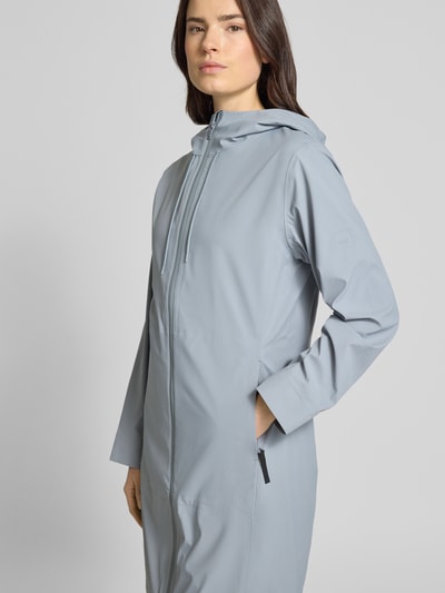 Frauenmodel trägt Regular Fit Mantel Daumenschlaufen Modell 'Suva' von Rains in Hellgrau mit Kapuze, Zweiwege-Reißverschluss, Eingrifftaschen, Nahaufnahme Oberkörper. Rückenlänge 94 cm, Schulterbreite 38 cm, Brustweite 45 cm, Ärmellänge 61 cm, taillierte Passform.