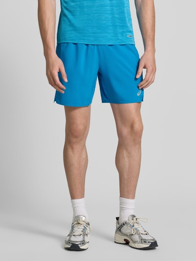 Mężczyznamodel nosi niebieskie szorty Regular Fit Shorts mit integriertem Slip Modell 'Core' od ASICS TIGER, nadruk z logo, elastyczny pas, szerokość w rozmiarze M: 38 cm, długość wewnętrzna nogawki w rozmiarze M: 17 cm, materiał gładki, całopostaciowy widok z przodu.