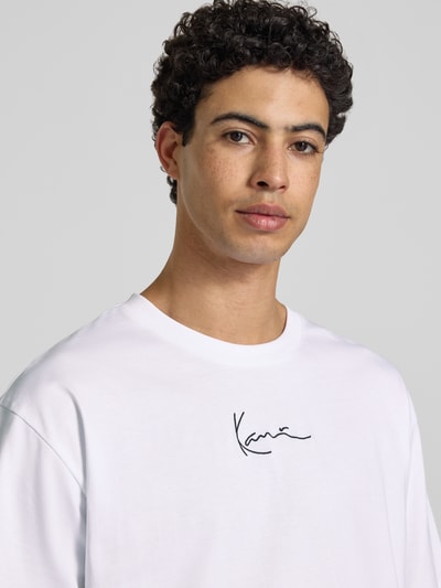 Männermodel trägt Oversized T-Shirt mit Logo-Stitching von KARL KANI in Weiß, Reine Baumwolle, Oversized-Fit, Rundhalsausschnitt, Nahaufnahme Oberkörper. Rückenlänge bei Größe M: 72 cm, Herren T-Shirt.