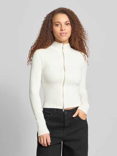 Frauenmodel trägt Slim Fit Jacke mit Stehkragen von Gina Tricot aus elastischem Baumwoll-Mix, Zweiwege-Reißverschluss, Ganzkörperansicht von vorne.