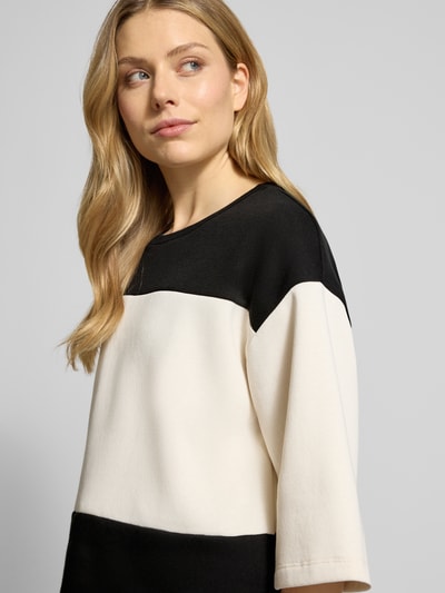 Frauenmodel trägt Sweatshirt mit geripptem Rundhalsausschnitt Modell 'ANGELIN' von Soyaconcept, lockerer Schnitt, 3/4-Ärmel, Baumwoll-Mix, Farbkombination Schwarz und Creme, Nahaufnahme Oberkörper.