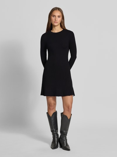 Frauenmodel trägt Eng anliegendes Freizeitkleid aus Viskose-Mix Modell 'MICHELLA' von ONLY, schwarzer Stoff, gerippte Struktur, Ganzkörperansicht von vorne, Damen Strickkleid von ONLY.