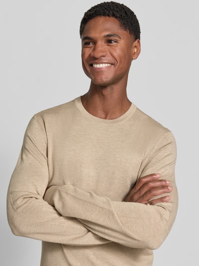 Männermodel trägt Strickpullover mit geripptem Rundhalsausschnitt von MCNEAL in Beige, feine Textur, Nahaufnahme Oberkörper, taillierte Passform, leicht überschnittene Schultern, gerippte Abschlüsse.