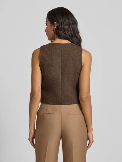 Frauenmodel trägt Regular Fit Weste mit V-Ausschnitt Modell 'PIPER' von Mango in Braun, kombiniert mit sandfarbenen Hosen, Ganzkörperansicht Rückansicht. Textur leicht meliert, Details wie Paspeltaschen und Knopfleiste erkennbar, Rückenlänge und Passform entsprechend Kontext.