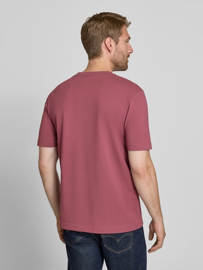 Männermodel trägt Relaxed Fit T-Shirt aus reiner Baumwolle Modell 'TCHUP' von BOSS Orange in Altrosa, glatte Textur, Ganzkörperansicht Rückansicht.