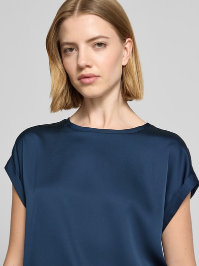 Frauenmodel trägt Damen T-Shirt aus Satin Modell 'ELLETTE' von Vila in Dunkelblau mit Aufschlag an den Ärmeln, Nahaufnahme Oberkörper. Damen T-Shirt hat Rundhalsausschnitt, Relaxed-Fit und Rückenlänge bei Größe 36 beträgt 60 cm.