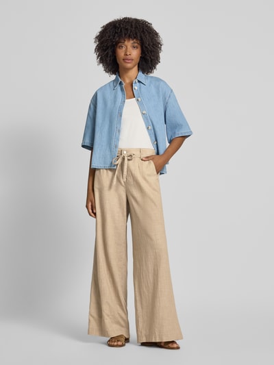 Frauenmodel trägt Wide-Fit Stoffhose mit Bügelfalten Modell 'Livia' von Angels aus Reine Baumwolle, beige Farbe, Ganzkörperansicht von vorne, Stoffhose mit Eingriffstaschen, Gesäßtasche, Knopf-Reißverschluss, Bundweite bei Größe 36/32: 41 cm, Innenbeinlänge: 88 cm.
