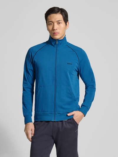 Männermodel trägt Regular Fit Sweatjacke aus Baumwoll-Mix Modell 'Mix&Match' von BOSS in Uni-Blau mit Reißverschluss, Stehkragen, Kontraststreifen und Tasche, Sweat-Textur, Ganzkörperansicht von vorne.