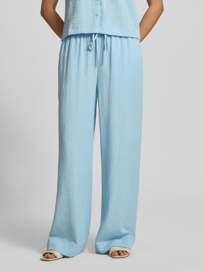 Kobiece modelka ma na sobie Straight Fit Hose aus Viskose-Mix Modell 'Daria' od MSCH Copenhagen, jasnoniebieska, szerokość w rozmiarze S 38 cm, długość nogawki wewnętrznej 77 cm, tkanina z lnu i wiskozy, elastyczny pas z troczkiem, tekstura lekko marszczona, pełny widok z przodu.
